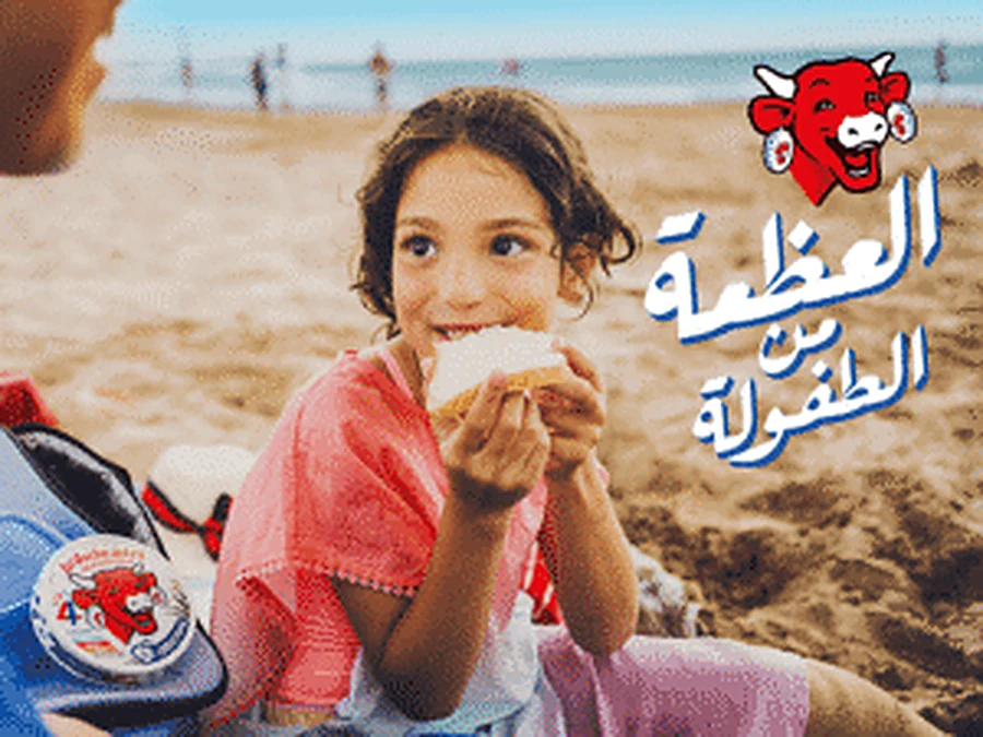Kind geniet van La Vache qui rit op het strand
