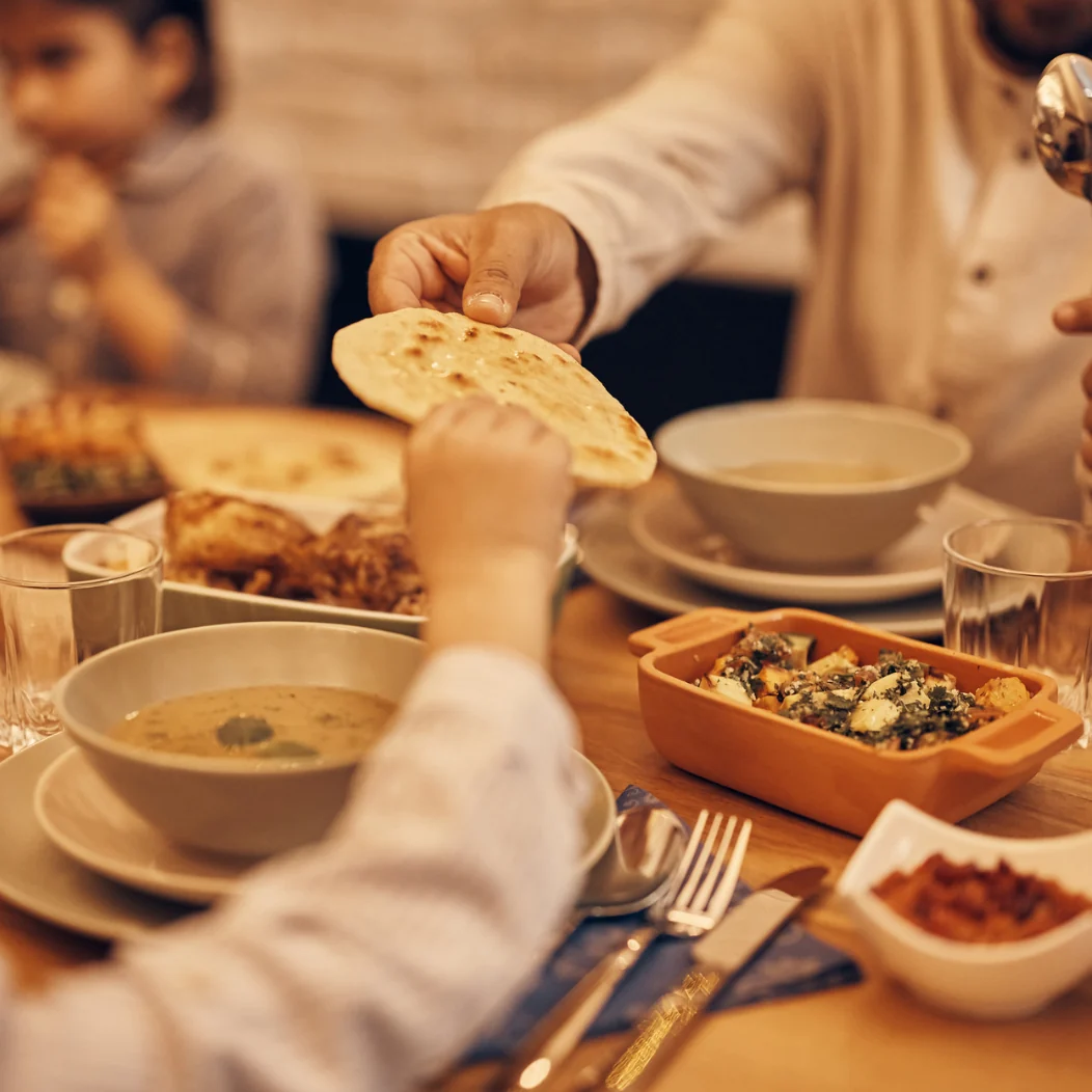 Aan tafel wordt vers brood doorgegeven bij mezze, soep en gestoofde groenten, een Midden-Oosterse maaltijd om te delen